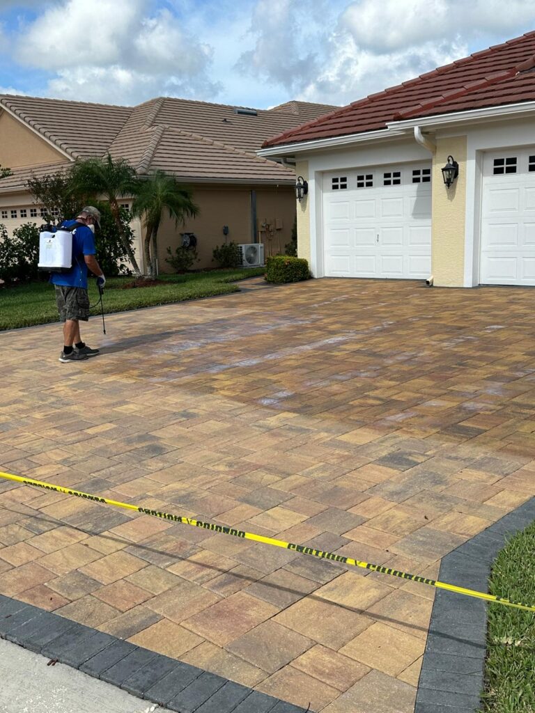 a man spraying a driveway doing paver cleaning and sealing