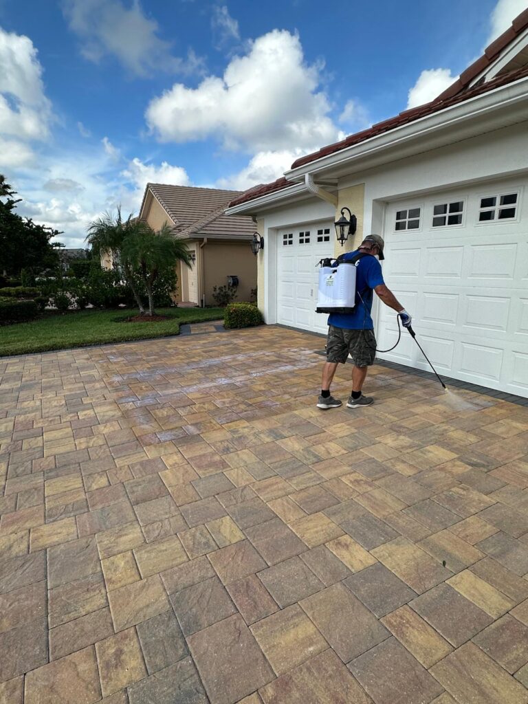 a man spraying a driveway with a spray gun