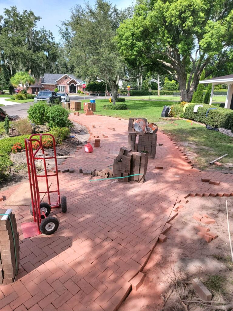 A new brick walkway being laid in a yard, adding beauty to the driveway in Lakeland, FL, perfect for outdoor gatherings.